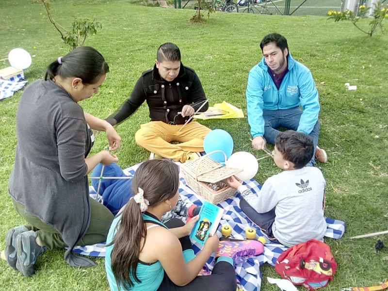 Familia_en_picnic_con_libros_y_cometas_acomapañdos_de_referente_institucional Familia en picnic con libros y cometas acomapañados de referente institucional