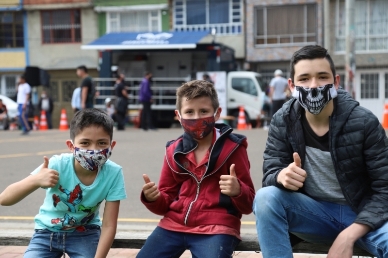 Tres niños con tapabocas mirando a la cámara