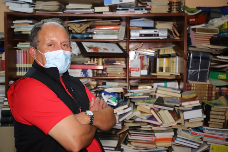 José Gutiérrez, el señor de los libros. Hombre cruzado de brazos con libros al fondo