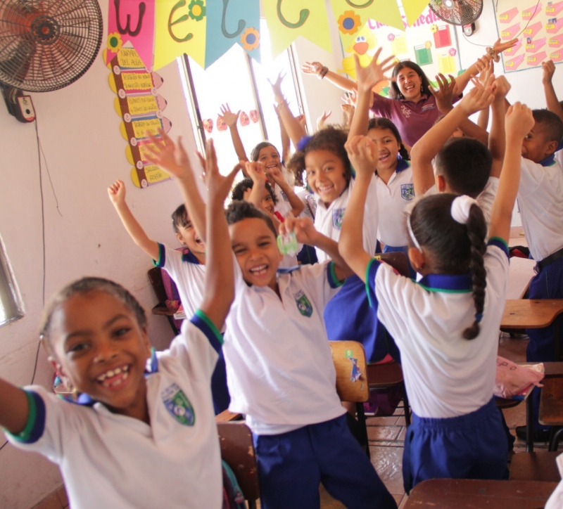 Maestra ludy con niños saltando alegres